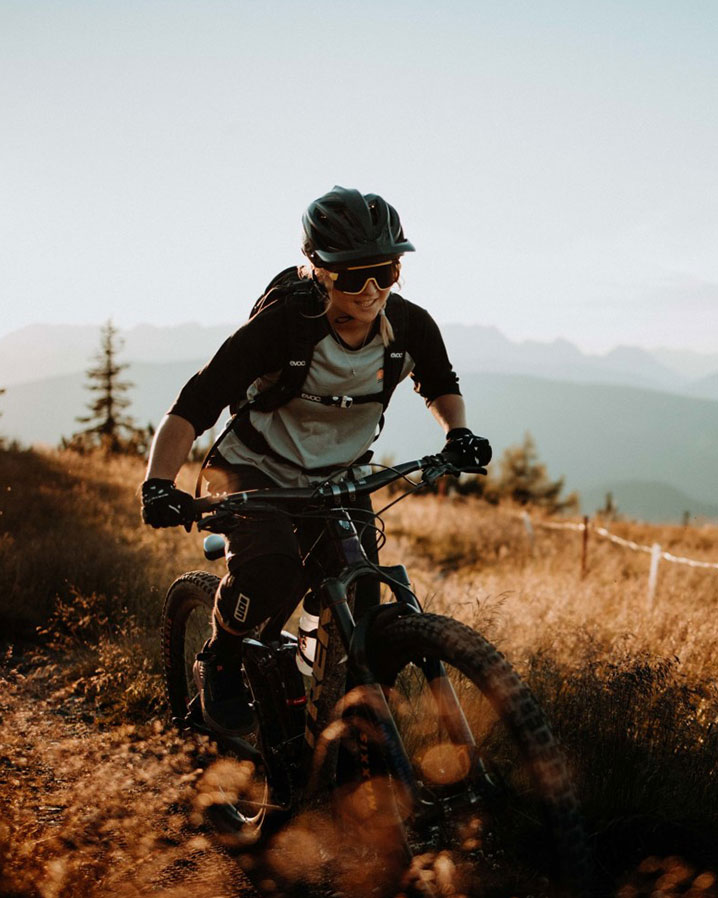 Ein weibliches Model fährt mit dem Mountainbike in den Bergen.